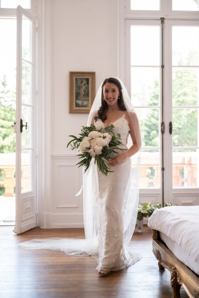 Bride standing interior room ready holding bouquet and smiling white roses flowers